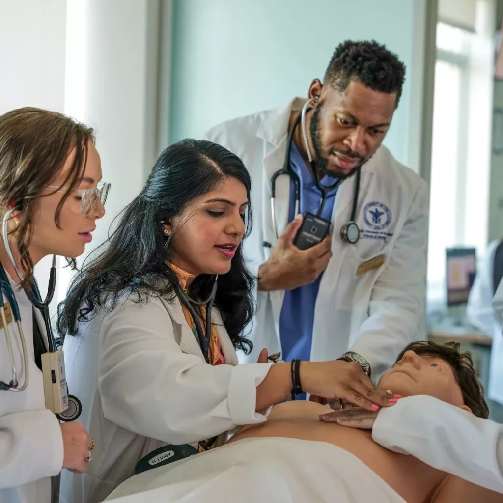 Medical students gather around a medical simulation dummy.